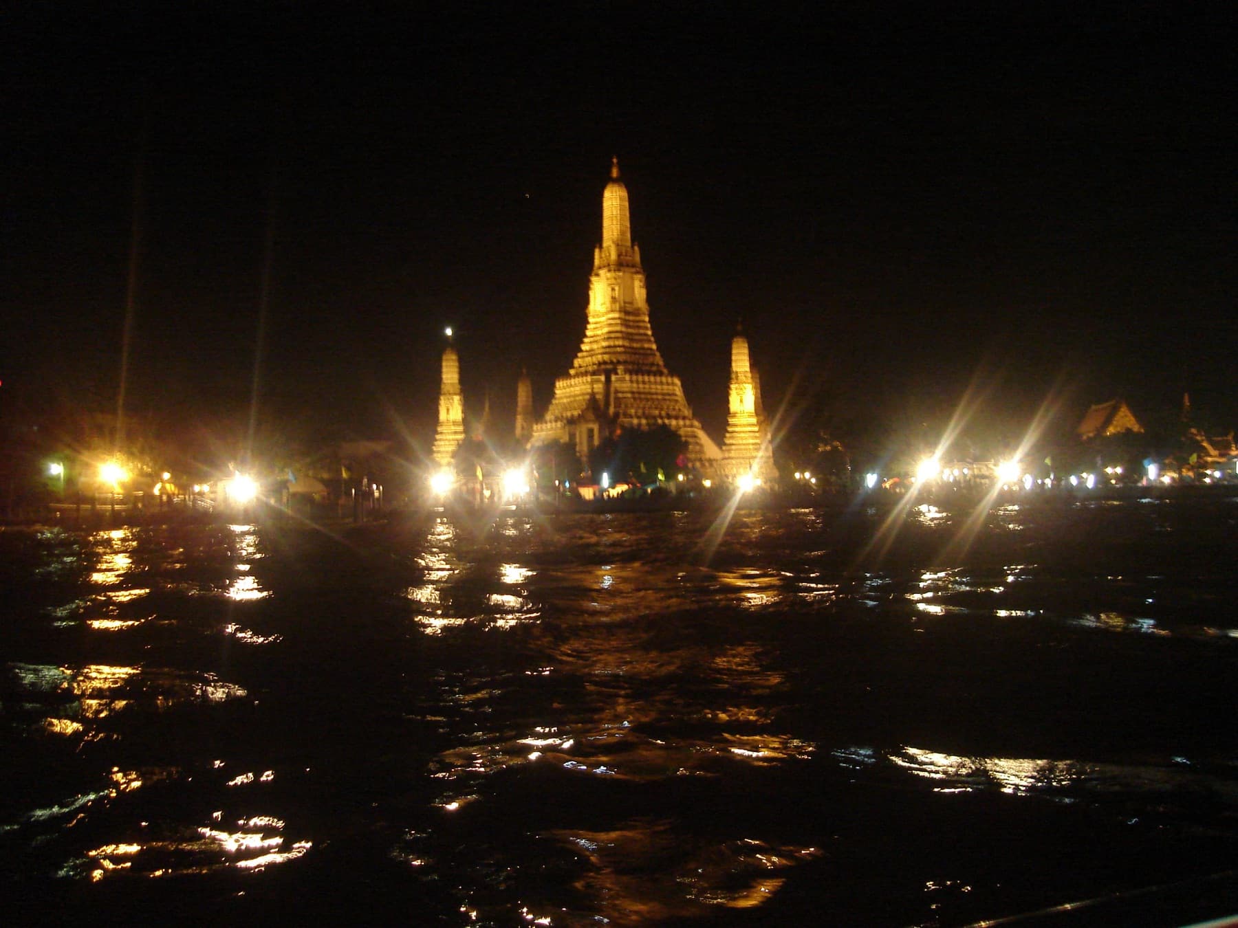Wat Arun lit up at night on the banks of the Chao Phraya river in Bangkok