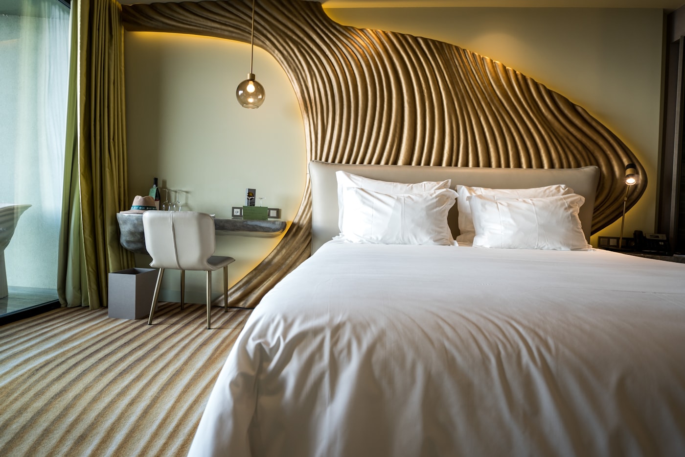 A five-star Dubai hotel suite with a sculptural gold headboard and crisp white linens.